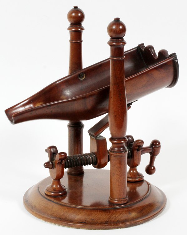 MAHOGANY WINE BOTTLE CRADLE EARLY 19TH C.: MAHOGANY WINE BOTTLE CRADLE, EARLY 19TH C., H 11", L 10":Adjustable tilt. For a high resolution photo CLICK HERE