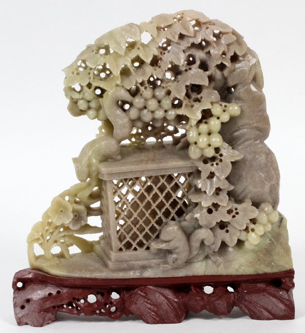 CHINESE CARVED SOAPSTONE SQUIRRELS & FOLIAGE: CHINESE CARVED SOAPSTONE SQUIRRELS & FOLIAGE, H 7 1/2", W 7":Depicting a grape vine with two squirrels eating grapes, surrounding a caged squirrel at the center. Fixed to a fitted carved stand. For a 