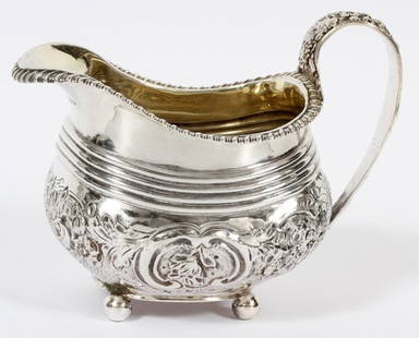 GEORGE III STERLING CREAMER BY WILLIAM BENNETT: GEORGE III STERLING CREAMER BY WILLIAM BENNETT, LONDON, 1814-15, H 4 1/2":A sterling silver creamer, or sauce boat, with gadrooned rim and ribbing about, floral repousse sides, on four ball feet. Hall