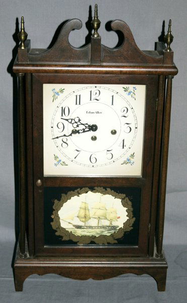 ETHAN ALLEN EMPIRE STYLE MAHOGANY MANTEL CLOCK: ETHAN ALLEN, AMERICAN EMPIRE STYLE, MAHOGANY MANTEL CLOCK, H 24", W 13", D 5 1/2":Broken-arch pediment with three urn-form finials, Arabic numerals, three-key wind, glass paneled door.