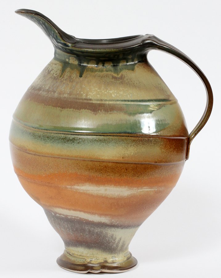 STEPHEN HILL POTTERY PITCHER: STEPHEN HILL (AMER 20-21ST C), POTTERY PITCHER, H 13", W 10":Having orange, green, brown and dark gray tones, flared spout, loop handle and smaller diameter base. Signed on the underside by the artist
