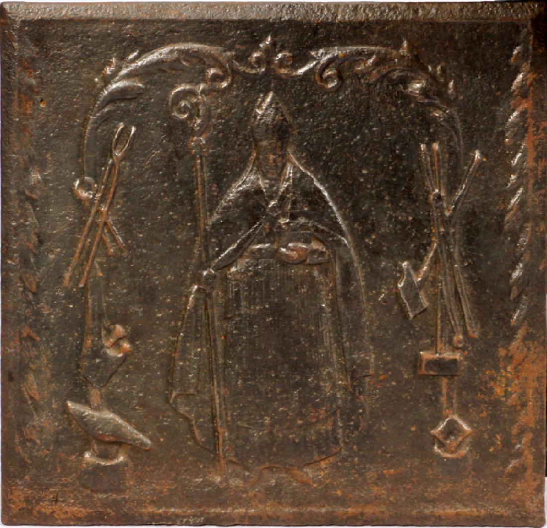 CAST IRON FIREBACK DEPICTING SAINT ELIGIUS: CAST IRON FIREBACK DEPICTING SAINT ELIGIUS, H 19", L 19":A cast iron fireback depicting Saint Eligius with associated attributes. Height 18 5/8", length 19".