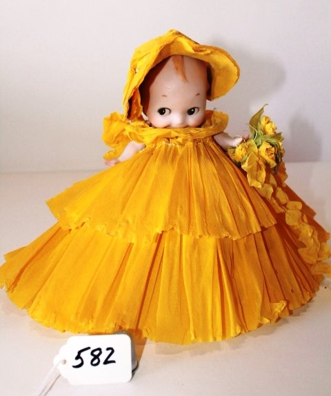 7"; GERMAN BISQUE KEWPIE DRESSED IN YELLOW CREPE PAPER: 7" - GERMAN BISQUE KEWPIE DRESSED IN YELLOW CREPE PAPER HAS MADE OF HONOR JANE BEST.