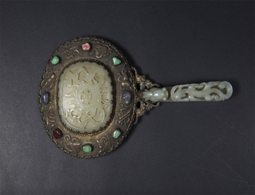 greenish-white jade-mounted and embellished silver hand: Qing, A greenish-white jade-mounted and embellished silver hand mirror20.4 cm long 嵌青白玉暗八仙图银框把镜