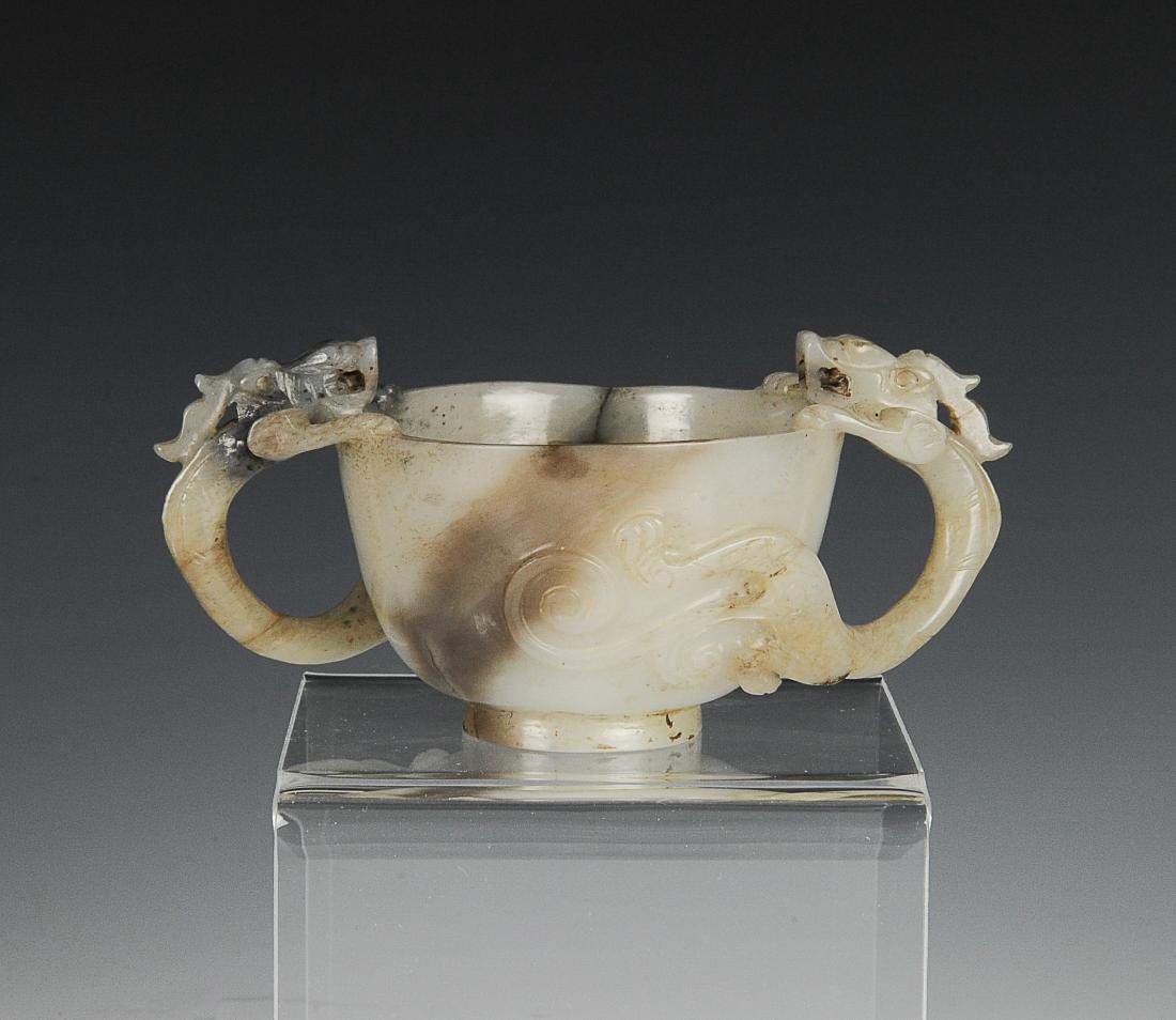 Black & White Jade Cup w/ Two Handles, Ming Dynasty: Black and white jade cup from the Ming dynasty. The cup is carved with two curving dragon handles on either side. It has a short, straight foot. Dimensions are 4 1/8 inches wide by 1 3/4 inches high. 