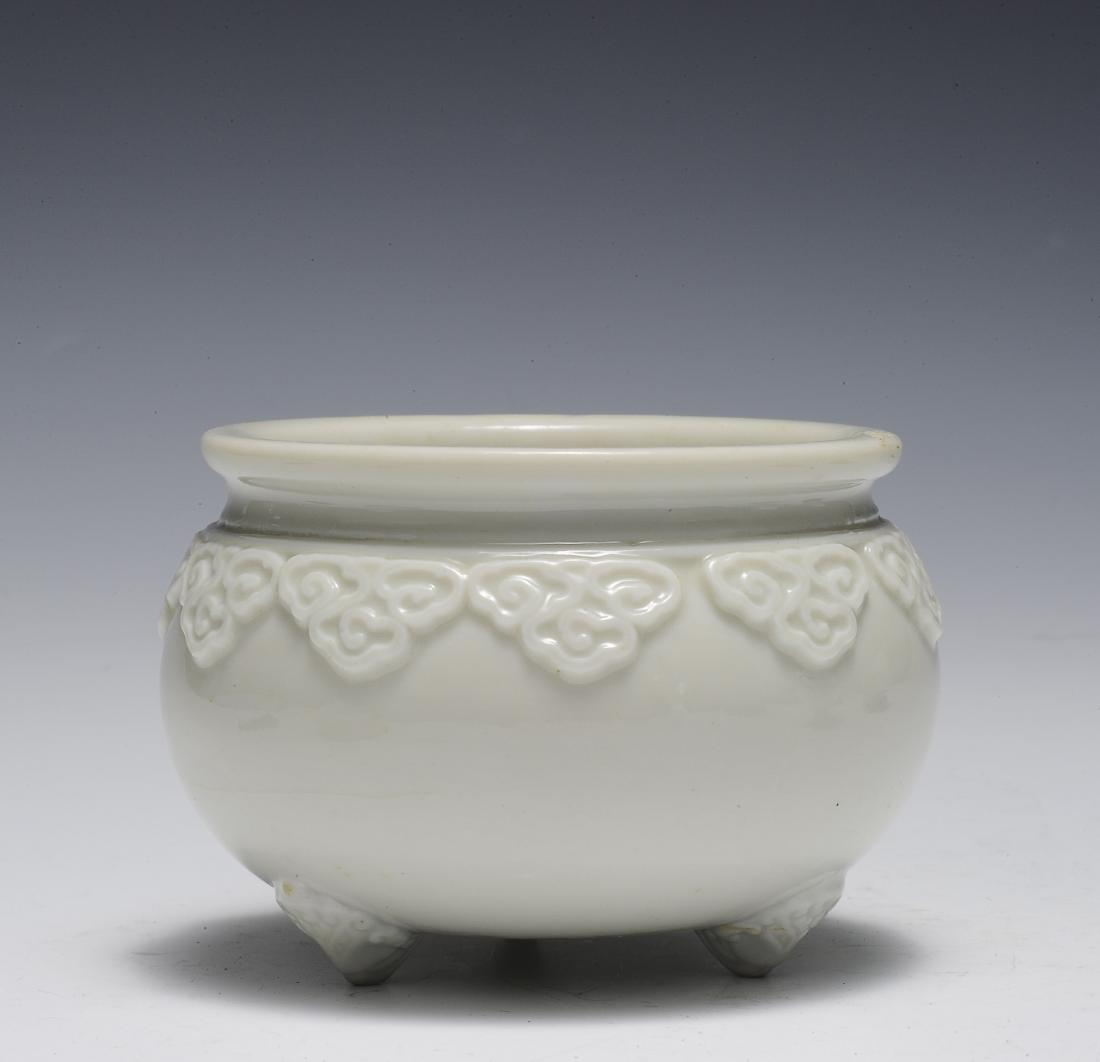 Dehua Ruyi Tripod Incense Burner, 17th - 18th Century: Dehua or blanc de chine porcelain tripod incense burner from the 17th - 18th century. This incense burner has a sculpted lingzhi border encompassing the shoulder and three sculpted feet on the bottom.