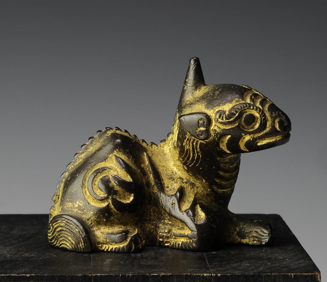 Gilt Bronze Qilin Paperweight, Ming Dynasty: Gilt bronze Qilin paperweight from the Ming dynasty. This small bronze Qilin has a single horn and is lying down. It has flames around the legs and ruyi form ears. Dimensions are 2 1/4 inches wide by 