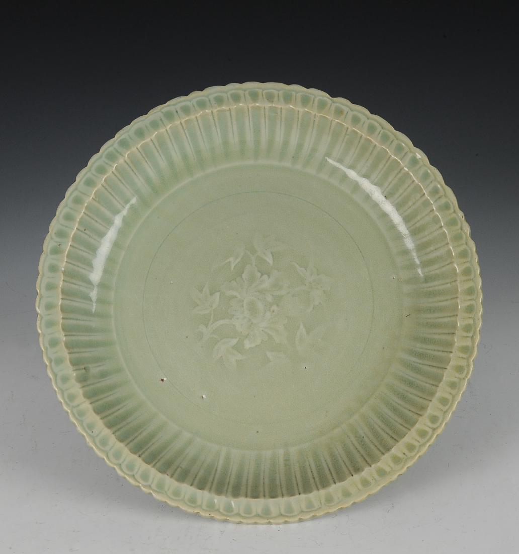 Longquan Celadon Plate, Ming Dynasty: Longquan celadon plate from the Ming dynasty. This pale green glazed plate is lobed and incised in the center with a floral medallion. Dimensions are 11 1/8 inches wide by 1 3/4 inches high. All measu
