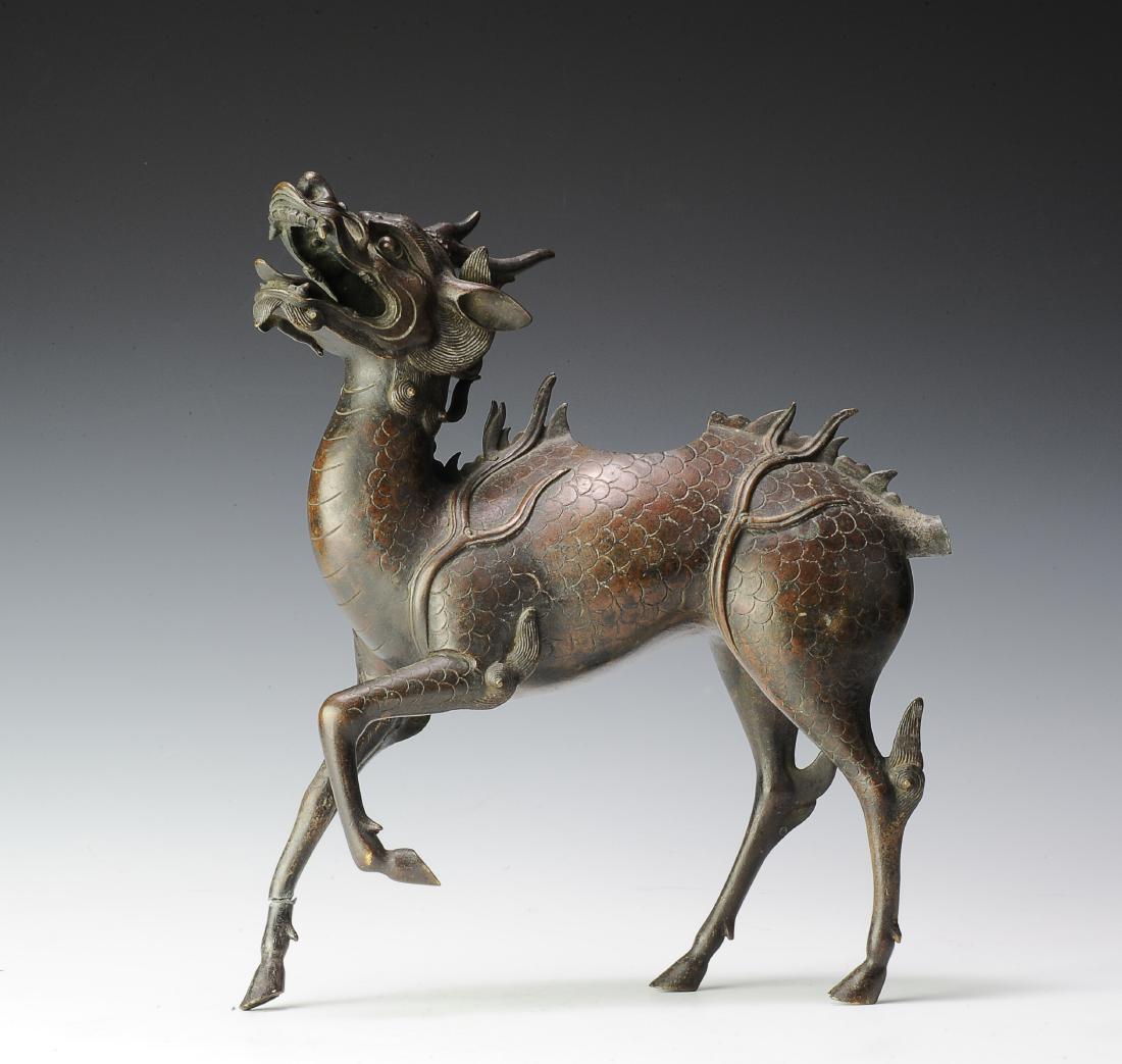 Bronze Incense Burner of Lucky Beast, Ming Dynasty: Bronze lucky beast incense burner from the Ming dynasty. The beast has one horn and a dragon-like face. It has scales, a long bushy tail, and cloven feet. There is an opening in the back and the mouth