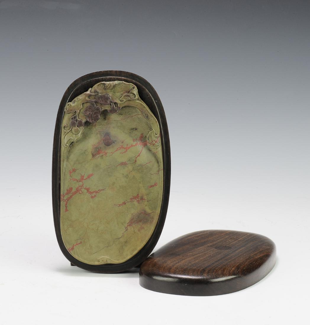 Duan Ink Stone & Old Rosewood Box, 19th Century: A Duan ink stone inside a rosewood ink box from the 19th century. The Duan inkstone is carved into the form of a fruit with leaves at the top. The stone is olive green with red striations. The stone i