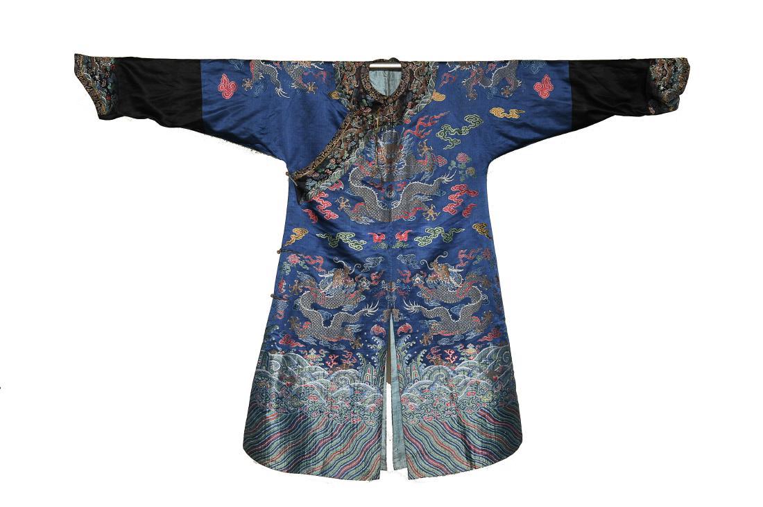 Blue Ground Dragon Robe, 19th Century: Deep blue ground silk dragon robe from the 19th century. It is embroidered with 5-clawed dragons, auspicious Buddhist symbols, and a wave and rock motif at the bottom. Embroidered around the dragons a