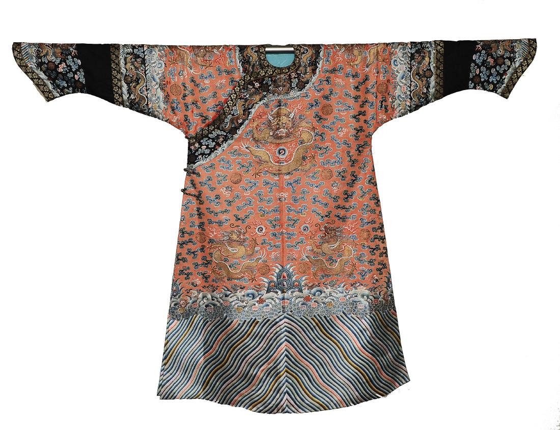 Red Dragon Robe, 19th Century: Red ground silk robe from the 19th century. The robe is embroidered with 5-clawed dragons, Buddhist symbols and a wave and rock motif on the bottom. Shou symbols and clouds surround the dragons. It ha