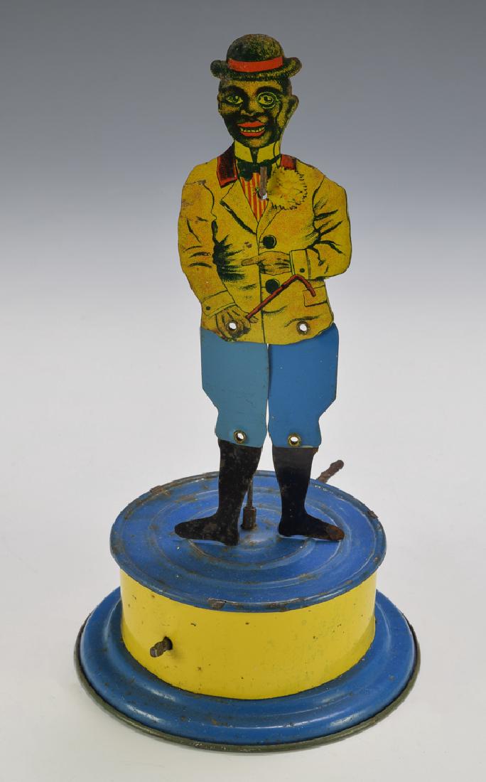 Tin Black Jigger Toy, Made in Germany, Circa 1920: Tin toy made in Germany circa 1920 with crank action. Dimensions are: 8 3/8" tall, 4 1/2" diameter. All measurements are approximate. Some wear to base, figure excellent. Overall Fine - Excellent.