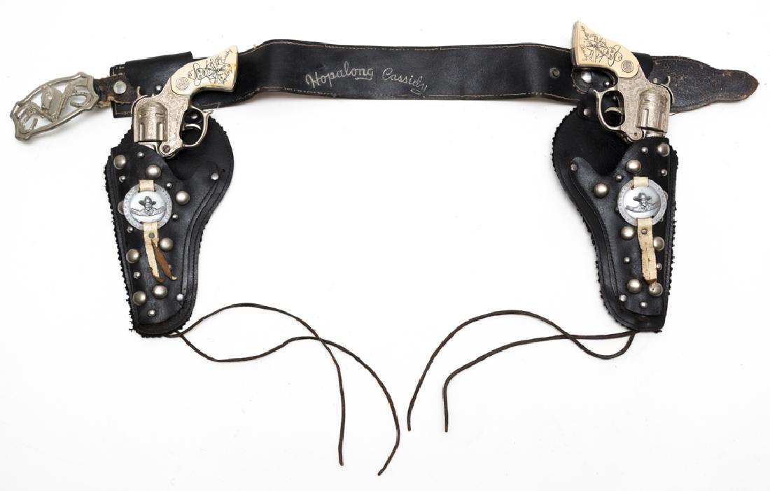 Hopalong Cassidy Wyandotte Cap Guns and Holster: Holsters and two cap guns marked "Hopalong Cassidy" on the back of the belt, on the metallic medallion on each holster, and the grip and barrel of each cap gun. Dimensions are: each cap gun measures