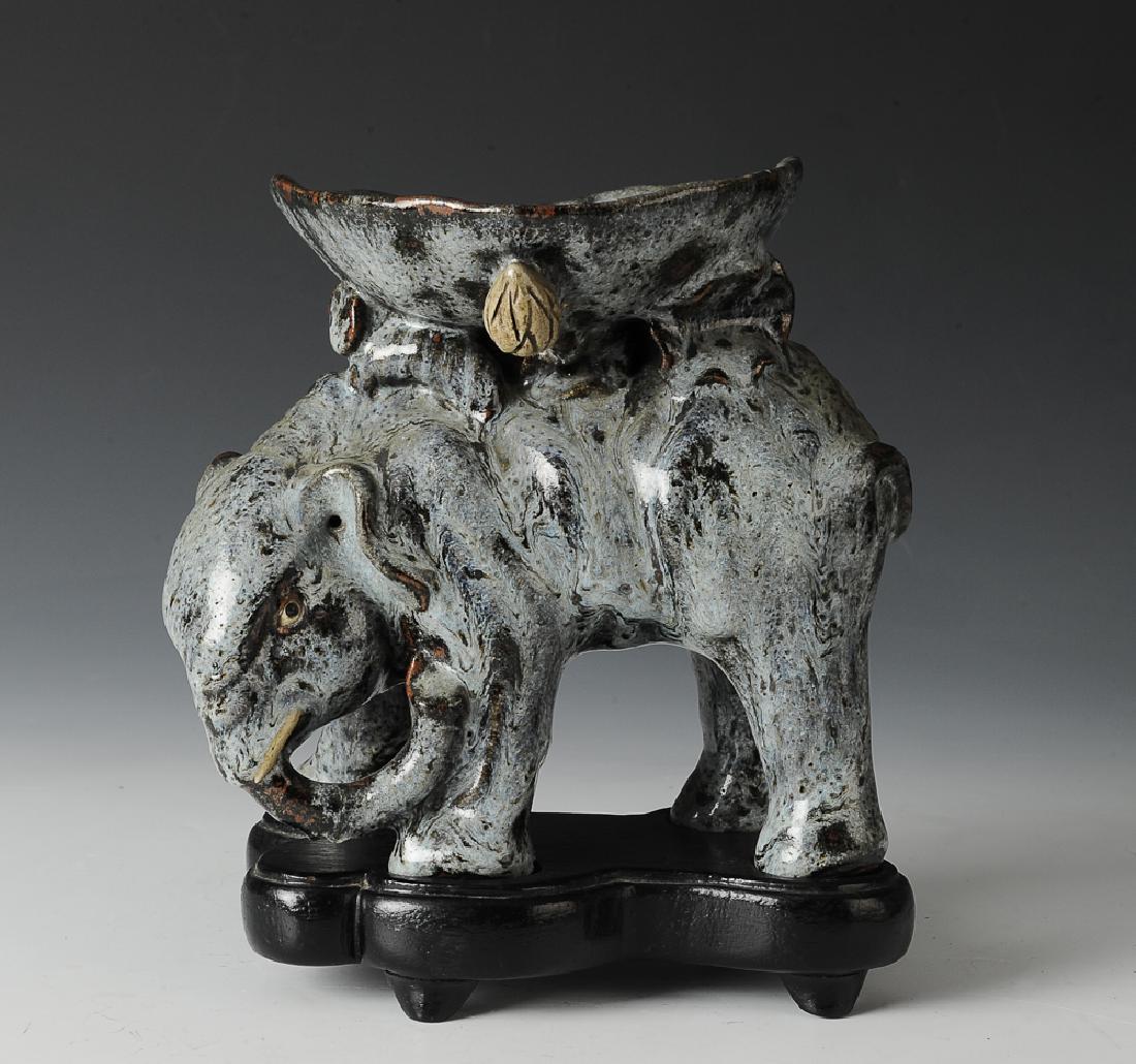 Chinese Shiwan Statue of an Elephant, Ming Dynasty: A Shiwan ceramic statue of an elephant with a wooden stand dating from the Ming dynasty. The basin on the elephant's back is in the form of a lotus leaf with buds and roots. There is a hole in the ele