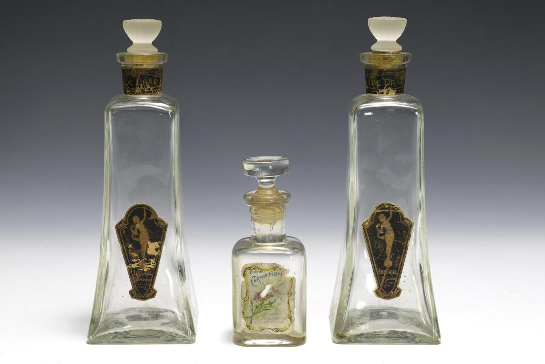 Three Glass Perfume Bottles: Three glass perfume bottles, two made by Carr-Lowry and one unsigned. All retain their labels, two from "Loe Drae" and one from "The LF Elliot Co." Dimensions are: largest 7 3/4" tall. All measurement