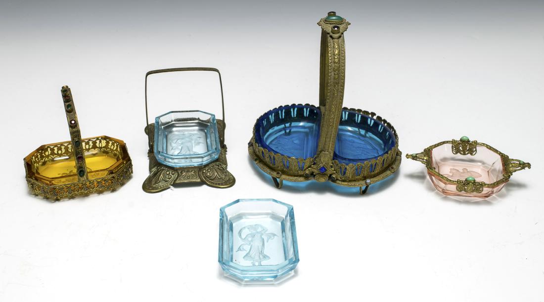 Four 1920s Czech Glass Trays with Brass Trim: Blue double tray with jeweled filigree, amber with jeweled filigree, two pale blue open salts with stamped base, and a pink dish with filigree and turquoise. Dimensions are: largest 4 3/8" long. All m