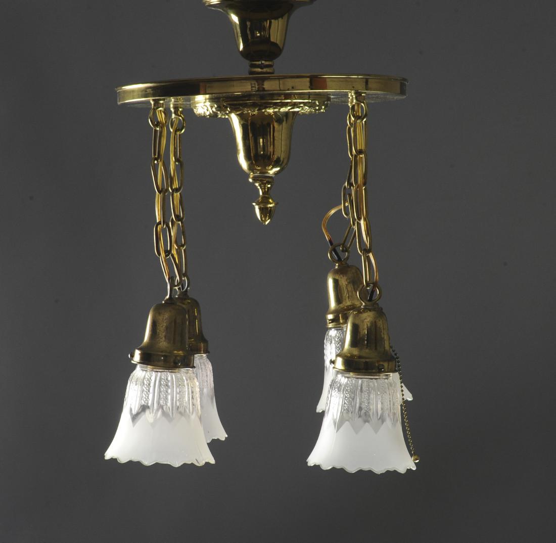 Brass Chandelier with Glass Shades: Four light fixtures suspended from a circular center. Dimensions are: 36" long, 23" wide. All measurements are approximate. Condition: Some paint spatter on top, minor wear. Very Fine.