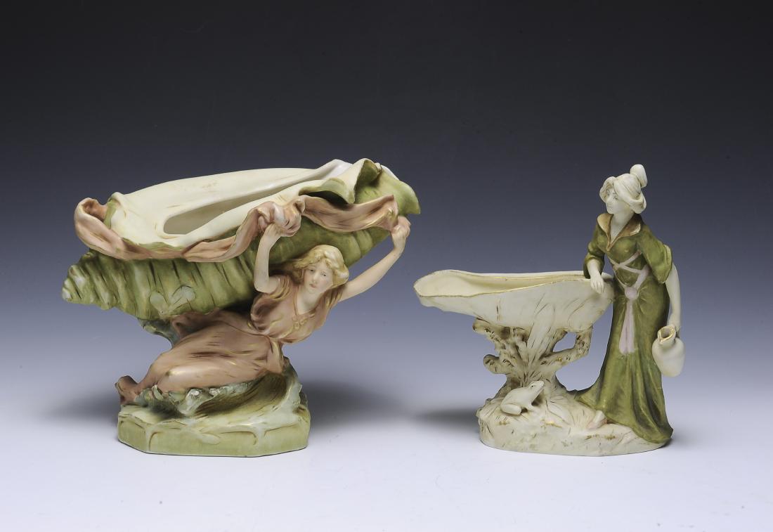 Two Royal Dux Art Nouveau Centerpieces: Royal Dux, Bohemia. Larger one is a woman holding a shell, smaller has a woman standing beside a clamshell. Dimensions are: largest 9" tall, 11 1/2" long. All measurements are approximate. Condition: 