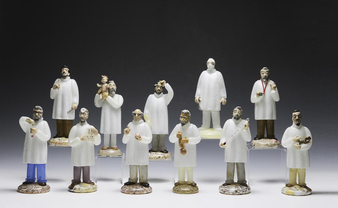 Eleven Czech Glass Doctor Figurines: Eleven Czech glass doctor figurines. The lot includes an optometrist, a dentist, a cardiologist, a chemist, a surgeon, a veterinarian, two pediatricians, and three general practitioners. Dimensions ar