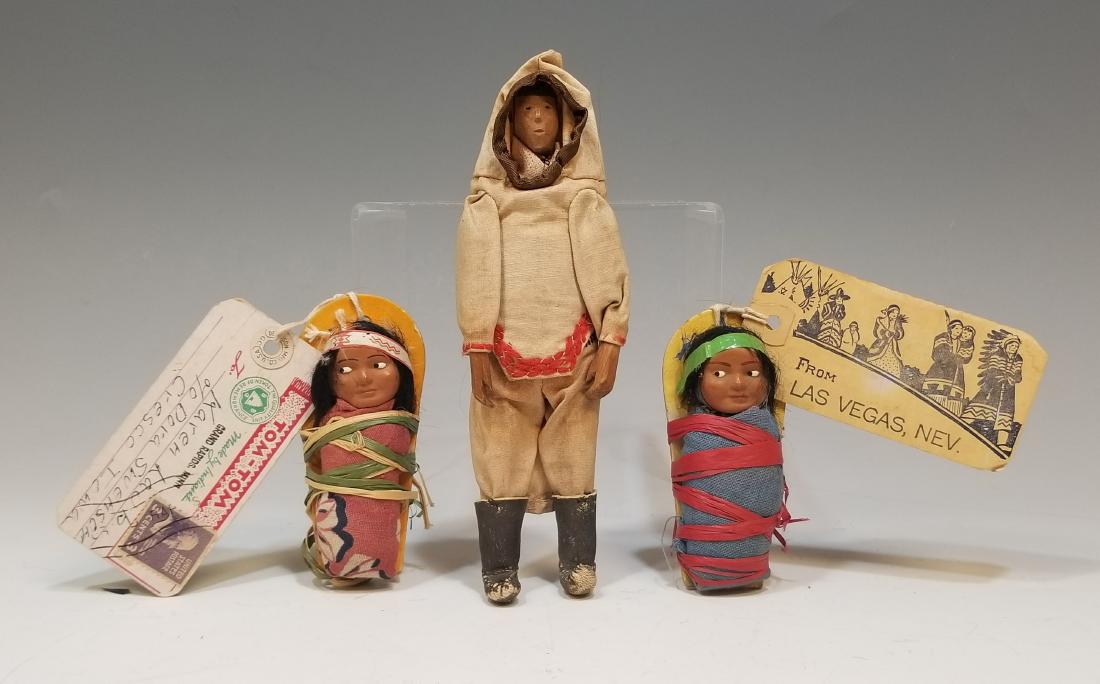 (3) Native American Dolls - Papooses & Handmade: (3) Native American Dolls - Papooses & Handmade: a) Carved wood figure wearing a hand stitched cotton coat and breeches and with leather boots. Dimensions are: 7" high. b) (2) Tom Tom papooses with ce