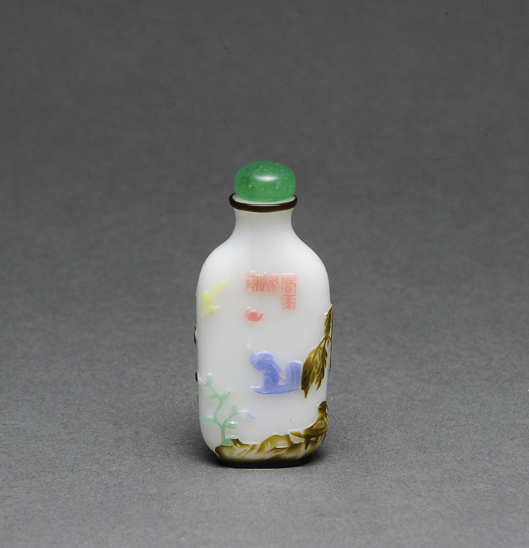 Chinese Peking Glass Lotus Snuff Bottle, 19th C.: A Chinese Peking glass snuff bottle dating from the 19th century. The snuff bottle has a glass stopper and a spoon. The body of the snuff bottle is decorated in blue, green, yellow, red, and brown aga