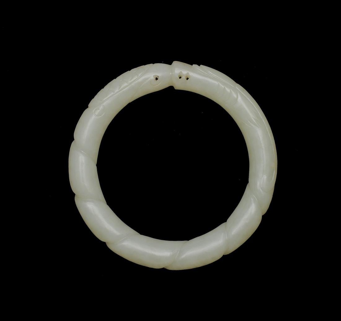 Chinese White Jade Dragon Bangle, Ming Dynasty: A Chinese white jade bangle carved with a dragon with long horns and dating from the Ming dynasty. Dimensions are: 3 inches in diameter, the interior diameter measures 2 1/8 inches. All measurements a