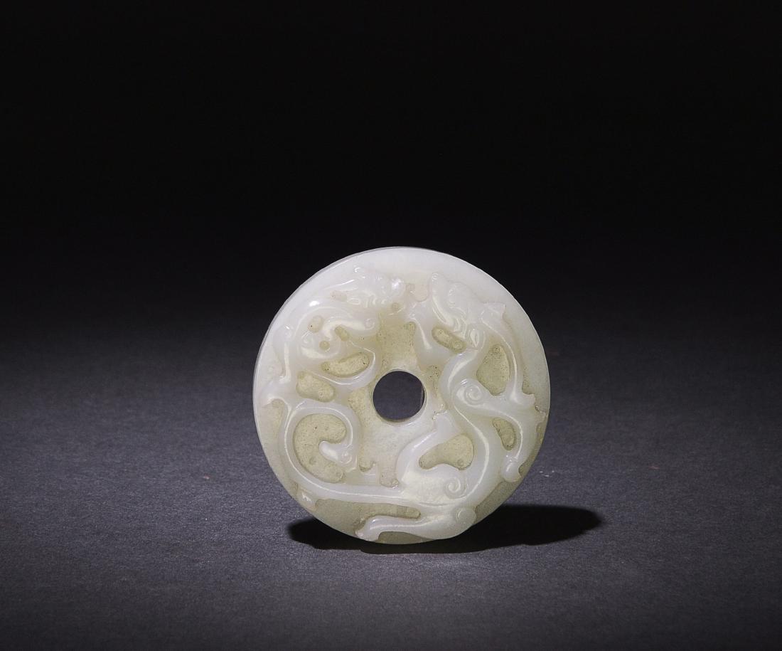 White Jade Bi with Chilong, 18th C. or Earlier: A Chinese white jade bi dating from the 18th century or possibly even earlier. The bi is carved on 1 side with a pair of chilong, and on the other with a geometric knot pattern. Dimensions are: 1/2 in