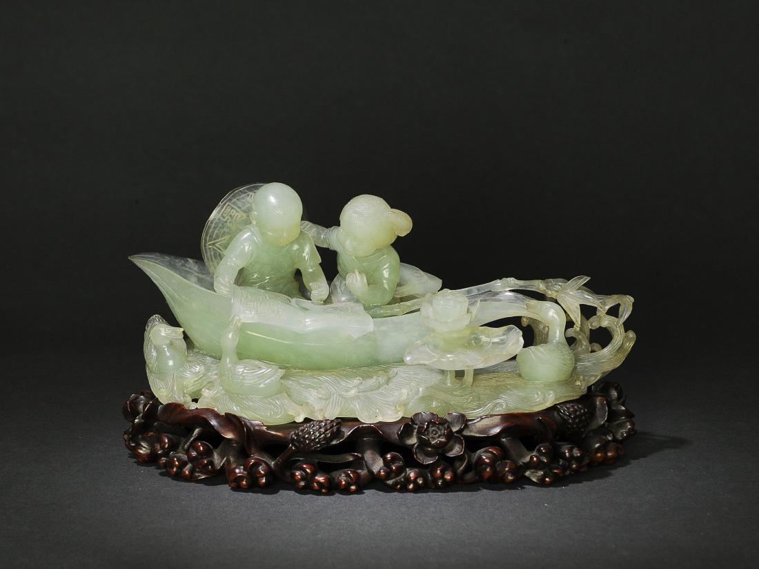 Jade Carved Children Statue w/ Stand Cultural Rev.: A Chinese jade carving of children studying with wood base dating from the Cultural Revolution. The children are reading in a boat with ducks, a frog, and lotuses. Dimensions are: 3 inches tall X 8 in