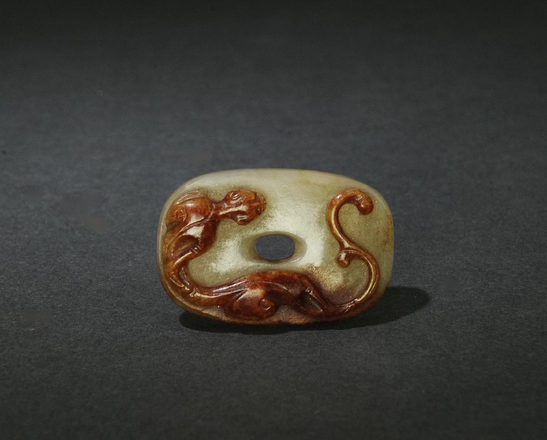 Chinese Jadeite Chilong Bi Ming Dynasty or Earlier: A Chinese red and green jadeite oblong oval carved with a chilong on one side and textured with a grain pattern on the other. The bi dates from the Ming dynasty or earlier. Dimensions are: 1 3/4 inche