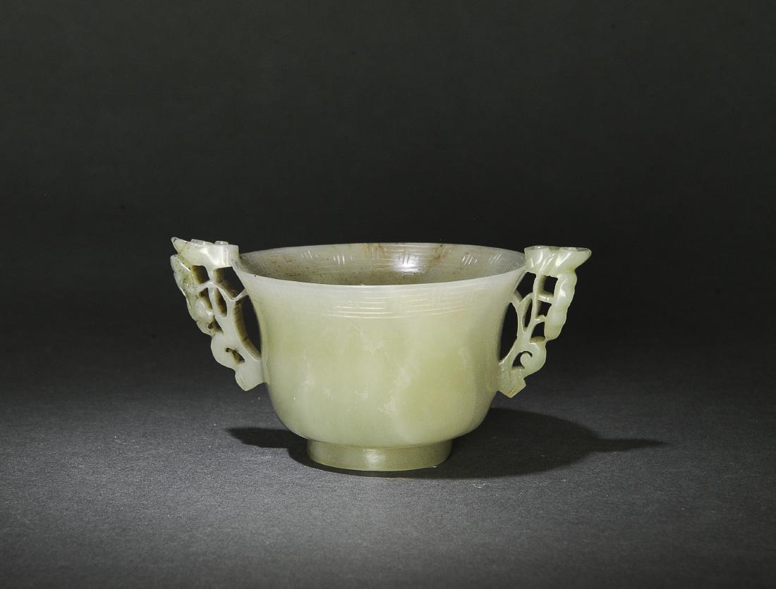 Chinese Celadon Jade Cup w/ Lingzhi, Ming Dynasty: Chinese celadon jade cup with lingzhi handles and dating from the Ming Dynasty. The cup has a short foot and a flared rim, and there is a Greek key border carved on the inside and outside of the lip. 