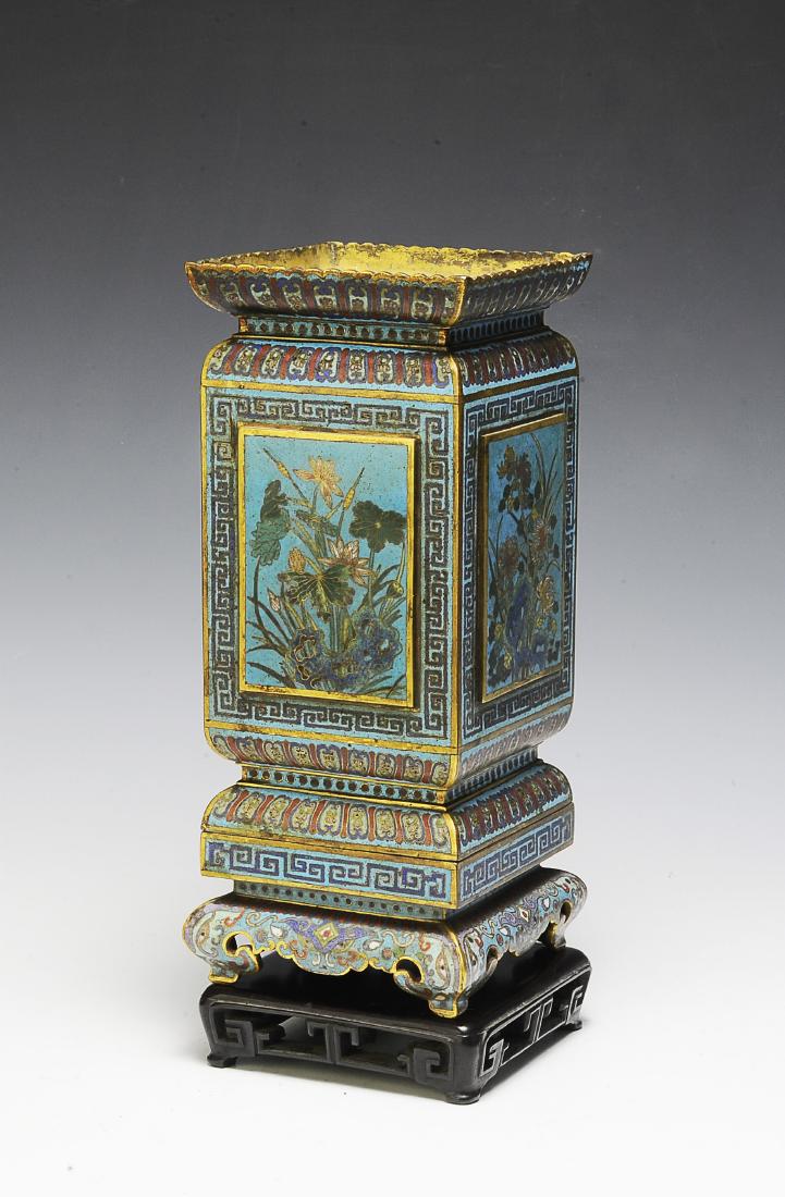 Chinese Square Cloisonne Vase, 18th Century: A Chinese sky blue ground square cloisonne vase with a wooden stand dating from the 18th century. The vase has a stylized petal border at the neck and the base, and a Greek key border below the neck a