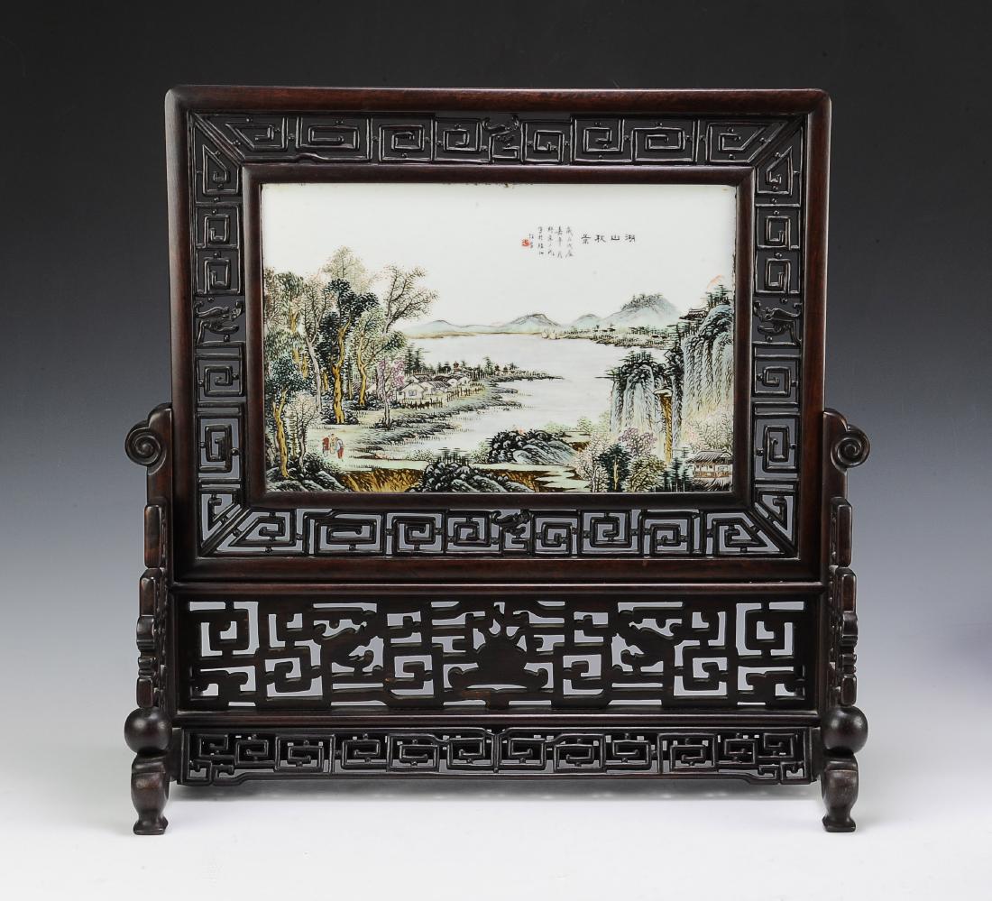 Table Screen w/ Porcelain Plaque, Wang Yeting: A wooden table screen with a porcelain plaque by Wang Yeting and dating to the early 20th century. The porcelain plaque depicts 3 figures in a landscape with a village in the forest by a river. The pl