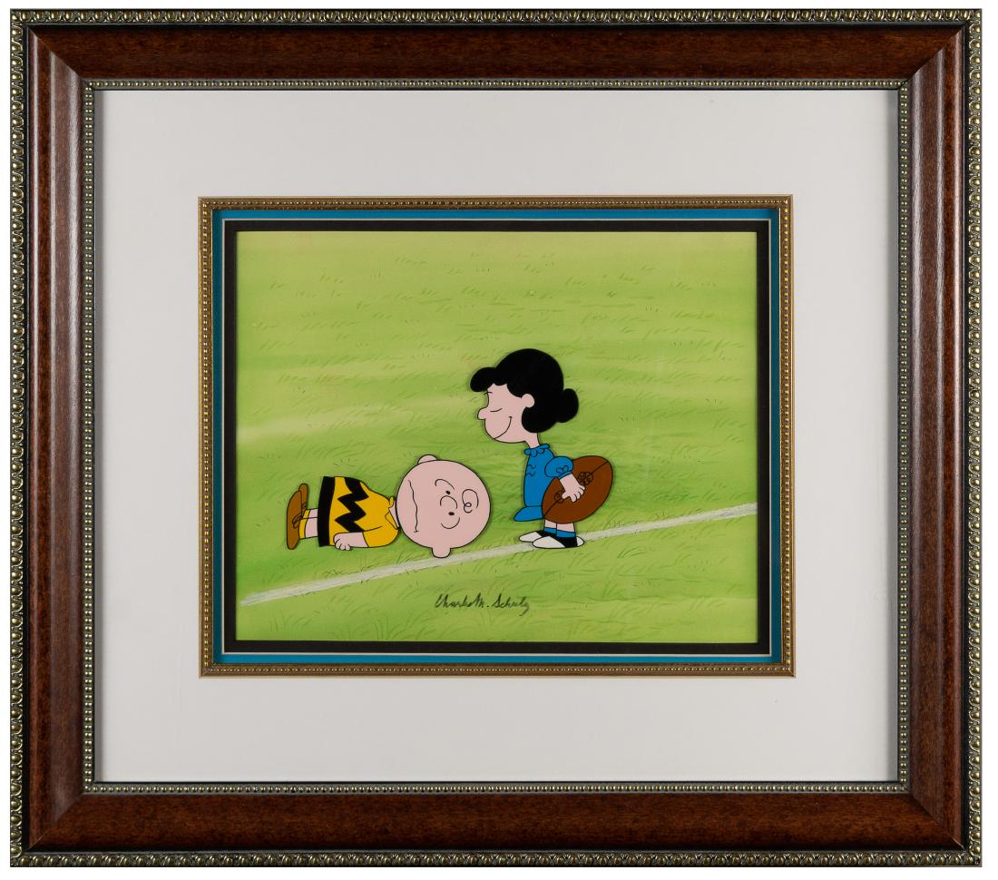 Schulz Signed Cel Charlie and Lucy Play Football: Charles Schulz (1922 - 2000, American) hand-signed and hand-painted Peanuts publicity cel animation on acetate depicting Charlie Brown and Lucy van Pelt shown in the iconic moment of Lucy pulling a fo