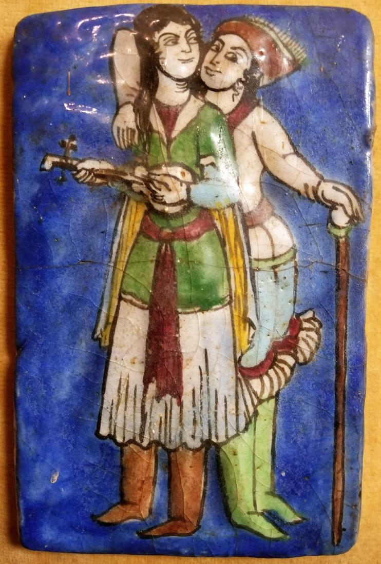 Framed Persian Qajar Ceramic Tile, 19th century: Persian Qajar glazed ceramic tile, 19th century, depicting a female musician strumming a stringed instrument and a companion or suitor leaning on a cane. Blue glaze for background, green, red, yellow,