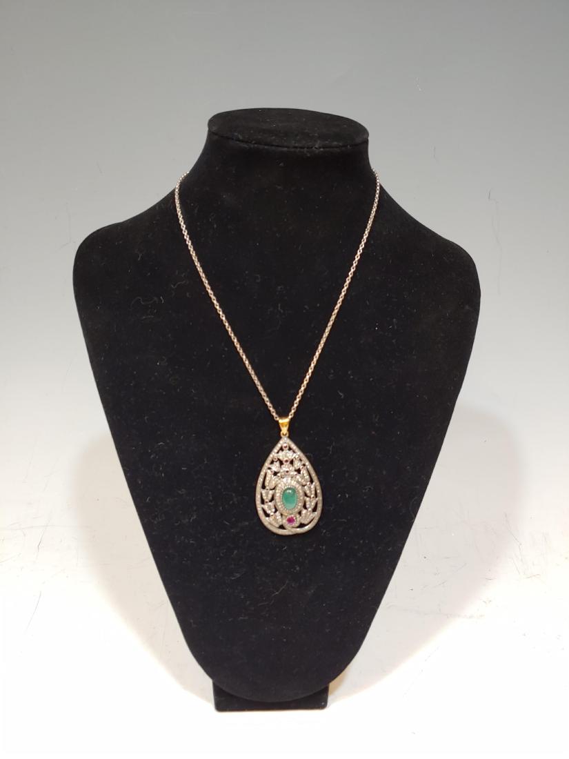 Pendant Necklace with Rubies, Diamonds and Emerald: Pendant with Rubies, Diamonds and Emerald: Teardrop shaped pendant in 14k gold and sterling silver set with a central emerald cabochon ( 10.6mm x 7.44mm) surrounded by bell flowers set with diamonds a