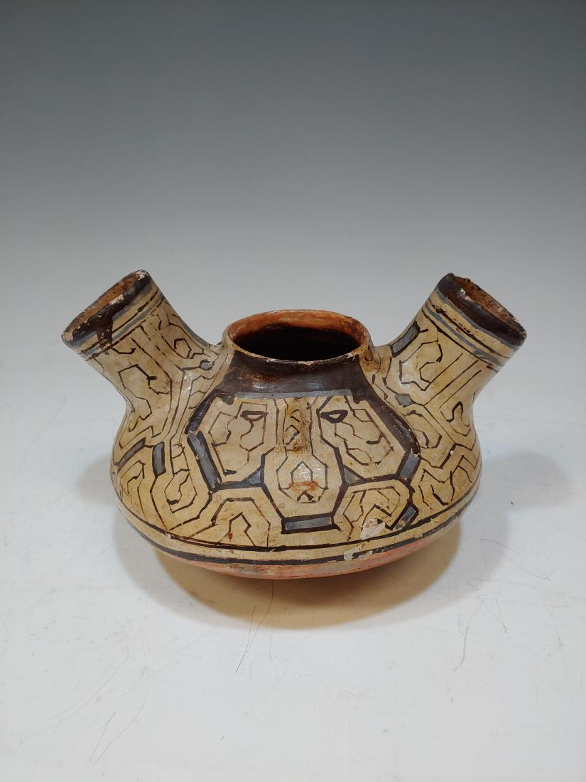 Pre-Columbian Trujillo Double Opening Vessel: Pre-Columbian Trujillo Double Opening Vessel: Peru. Earthenware vessel decorated with black, white, and blue slip in a geometric pattern. On both sides of vessel is a stylized, molded faced with paint