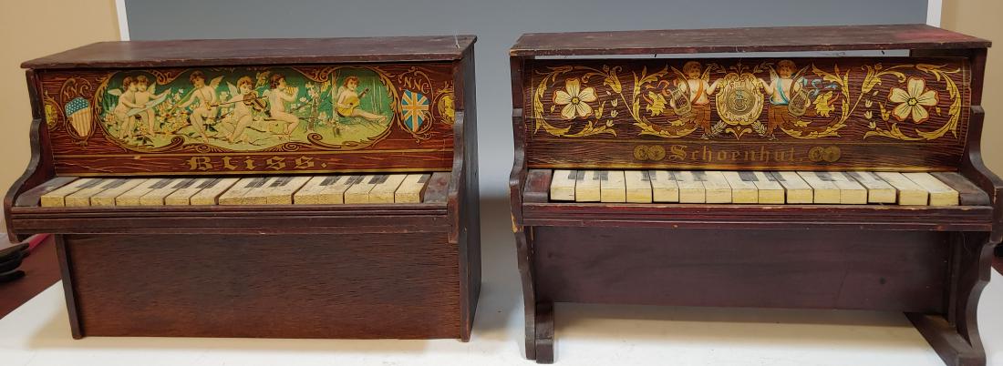 Bliss & Schoenhut Pianos: Pair of Bliss and Schoenhut miniature wooden and xylophone-keyboard pianos, with the upper panels painted with putti and flowers. Dimensions are: 16 7/8" long X 8 1/8" wide X 11 1/2" high. All measure