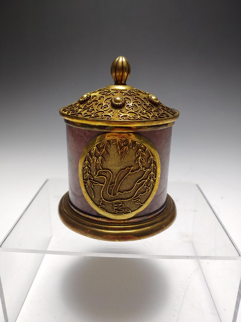Carved Anyolite Silver Cigarette Box: Cylindrical cigarette box carved from anyolite and overlaid with gold washed sterling silver. Silver plaques on opposite sides of exterior show a swan on a pond. Bottom of container marked silver. Tot