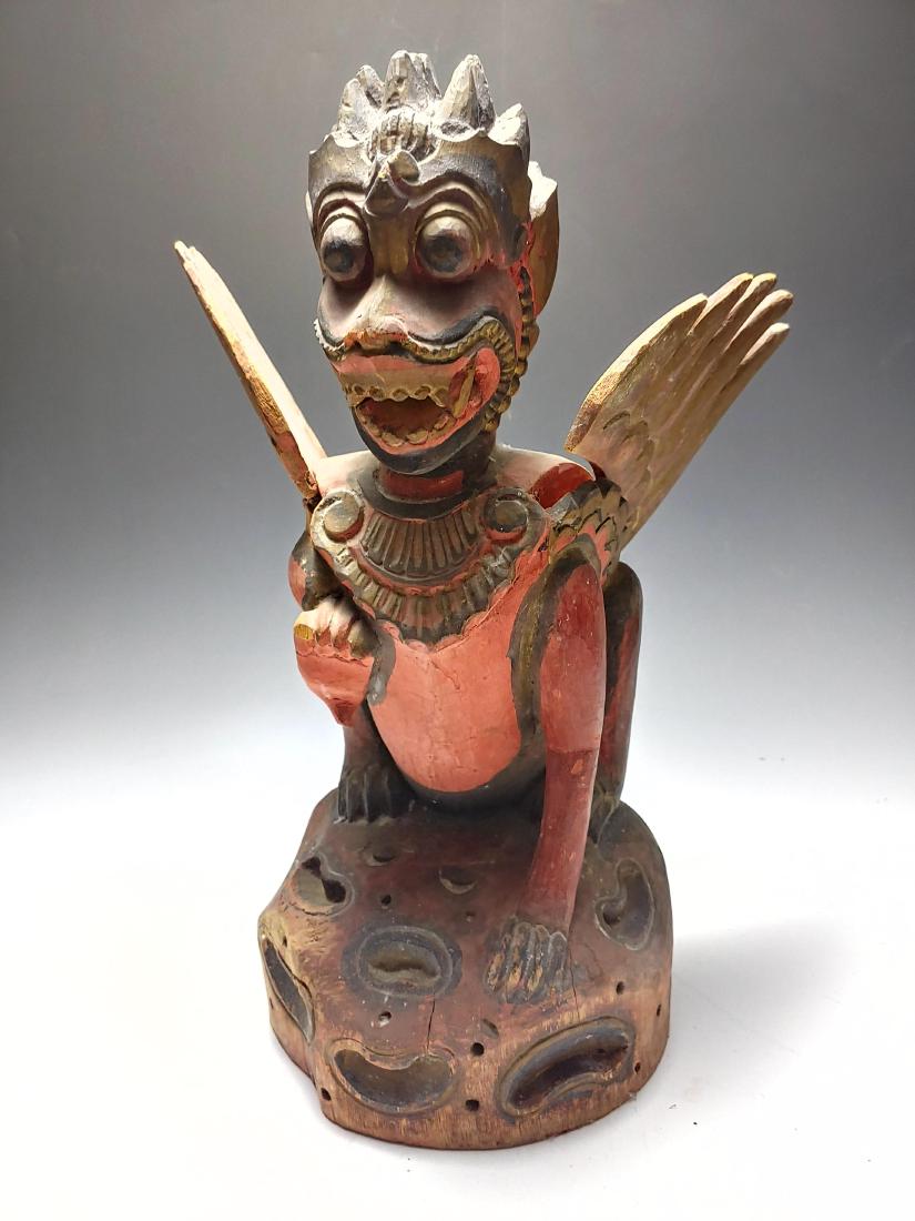 Carved Indonesian Wood Winged Garuda Figure: Carved Indonesian Wood Winged Garuda Figure: Statue is painted black and red with gold details. Dimensions are: 10 5/8 inches wide X 7 1/8 inches tall X 6 3/4 inches deep. All measurements are approxi