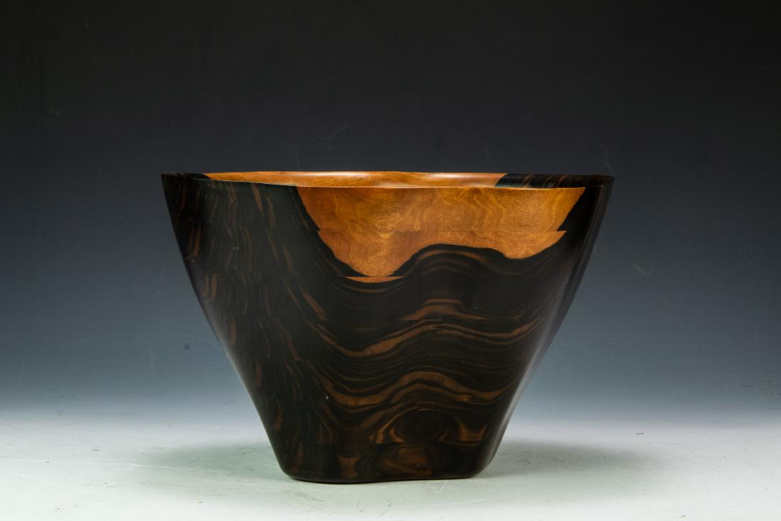 Peter M Petrochko Carved Wood Bowl: Peter M. Petrochko carved wooden bowl of macassar ebony, with wood, name, and date June 1990 mark on underside of base. Organic shape. Dimensions are: 8 3/4 inches high X 14 1/4 inches wide at widest