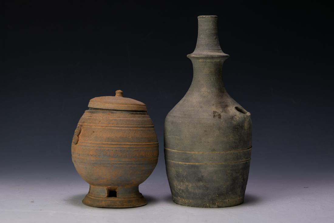 (2) Korean Clay Vessels, Three Kingdoms Period: (2) Korean clay vessels dating from the Three Kingdoms Period, including a wheel thrown wine flask with a spout and a Silla covered jar. Flask has incised stripes on body. Jar body has incised wave de