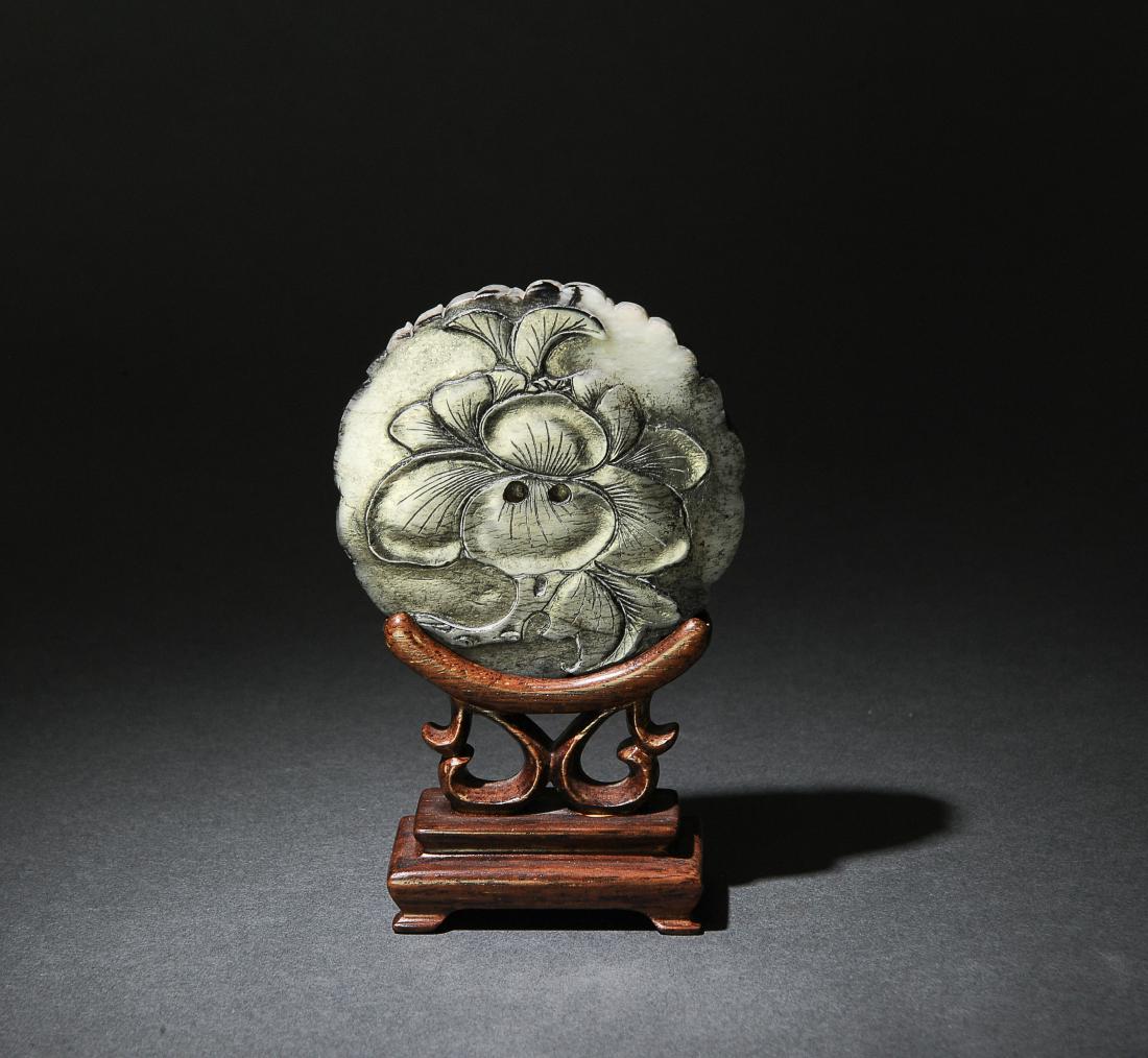 Chinese Jade Carved Bi w/ Wood Base, Ming Dynasty: A Chinese round, black chicken bone jade plaque carved with a lotus flower on one side and a seed pod with leaves and a butterfly on the other. The plaque comes with a wooden stand and dates from the