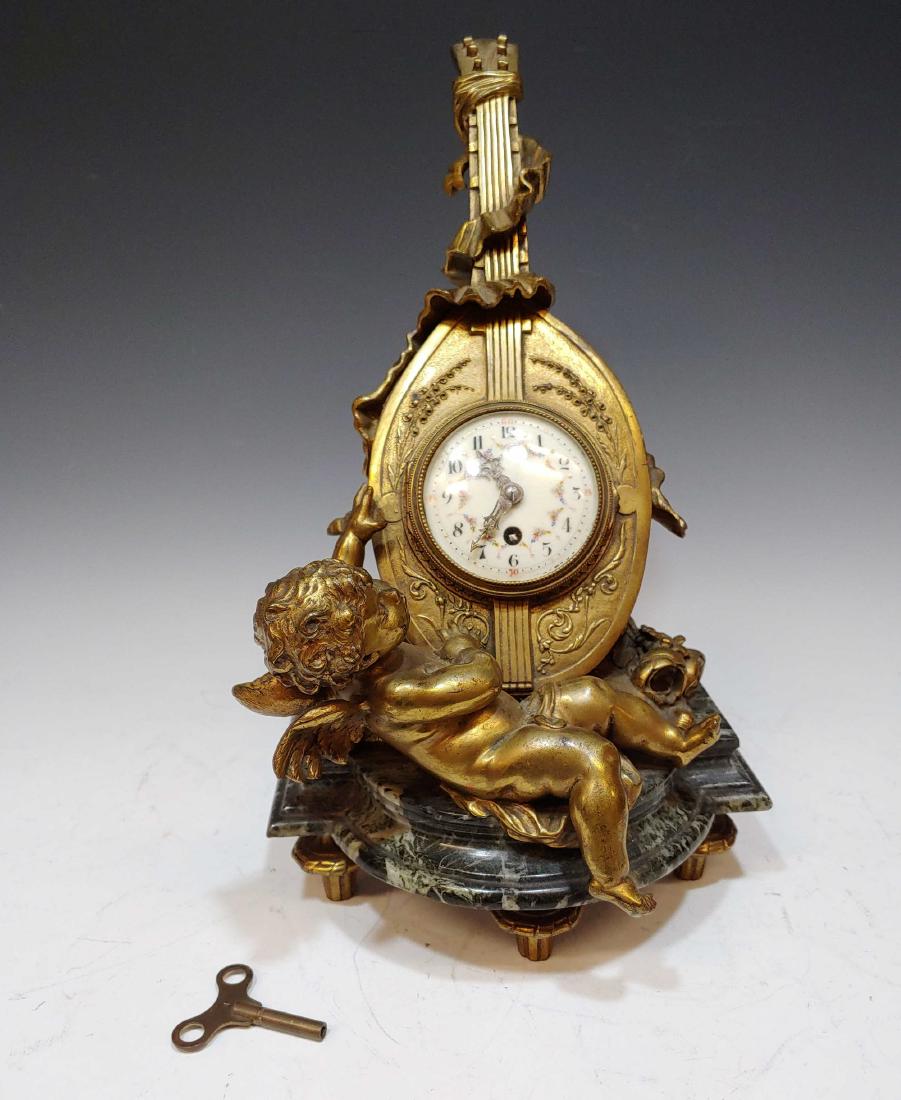 19th Century Auguste Moreau Clock with Cherub: Brass clock signed Auguste Moreau (France, 1834-1917) on marble stand. Sculptural clock of a cherub and a lyre, with the porcelain face of clock on the front of the instrument. Marked 'Aug Moreau' and