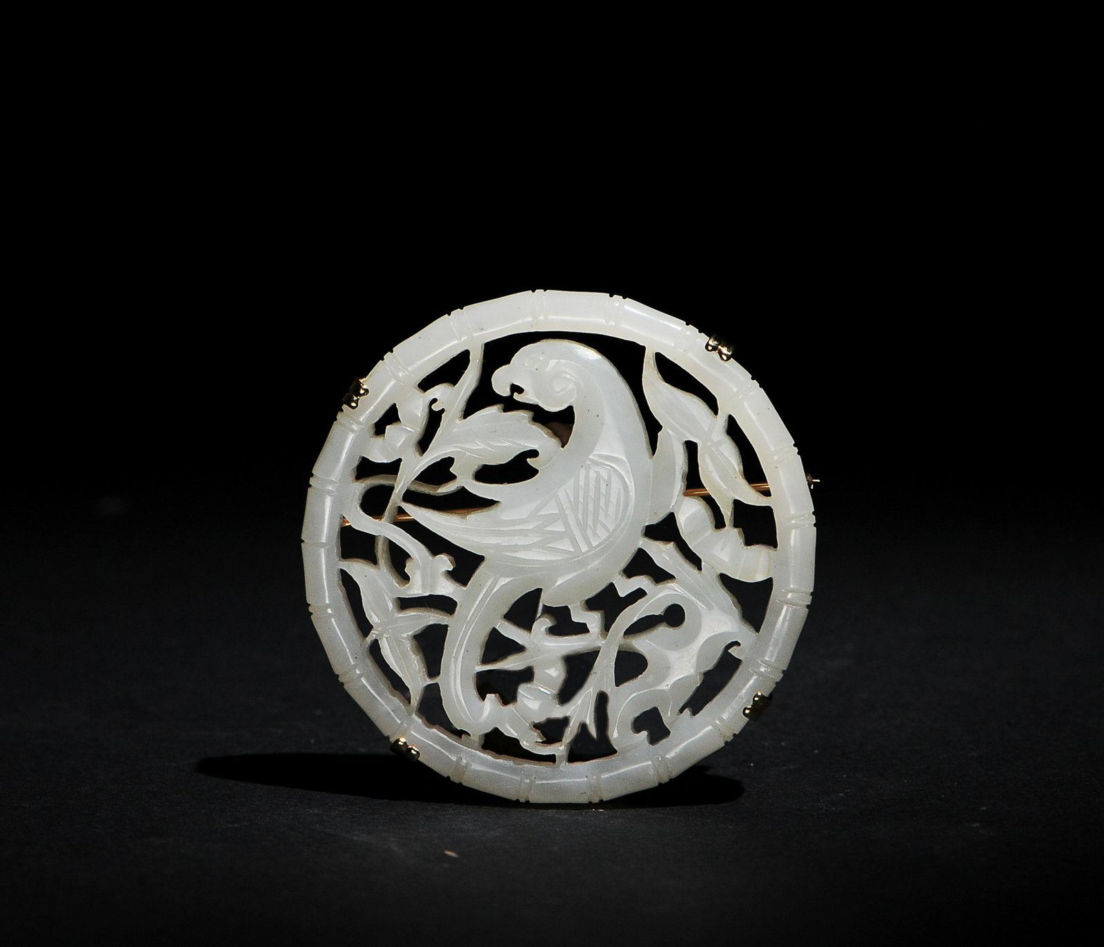 Chinese White Jade Plaque with Bird, 18th Century: A Chinese circular white jade plaque cut out with a bird among floral tracery dating from the 18th century. The plaque has been converted to a pin. Dimensions are: 2 inches in diameter. All measuremen