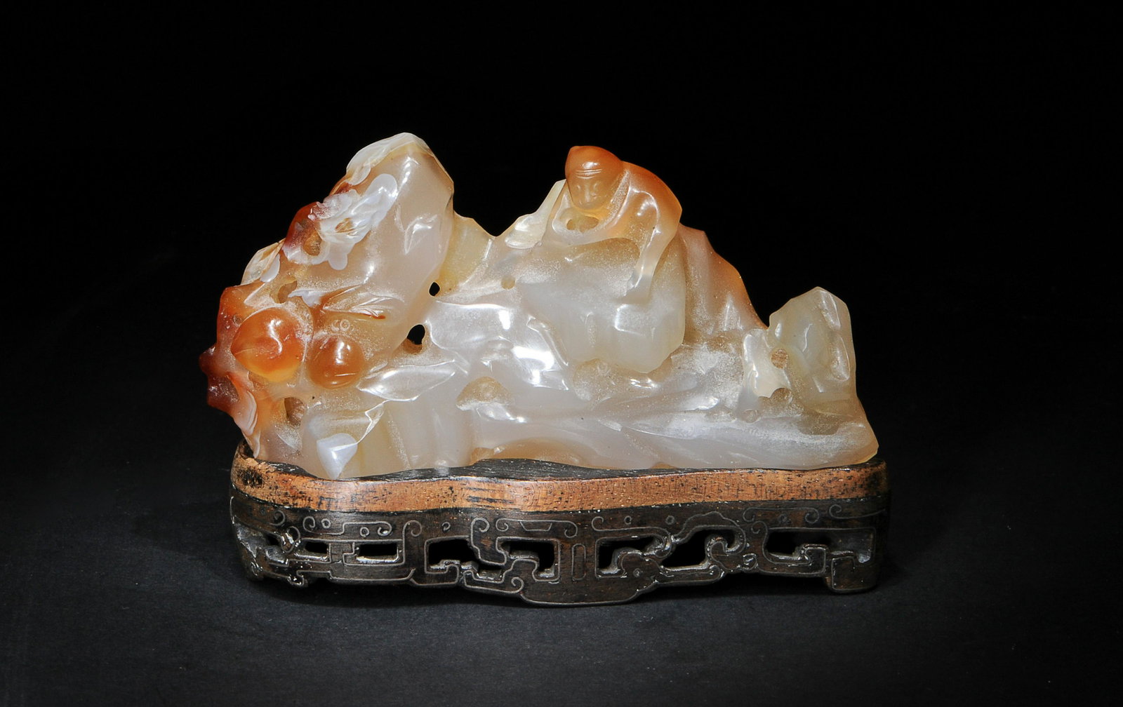 Chinese Agate Mountain Brush Holder, 18th Century: A Chinese agate mountain brush holder carved with a monkey with peaches and dating from the 18th century and with a wooden stand inlaid with silver wire. Dimensions are: 2 inches tall X 3 1/4 inches w