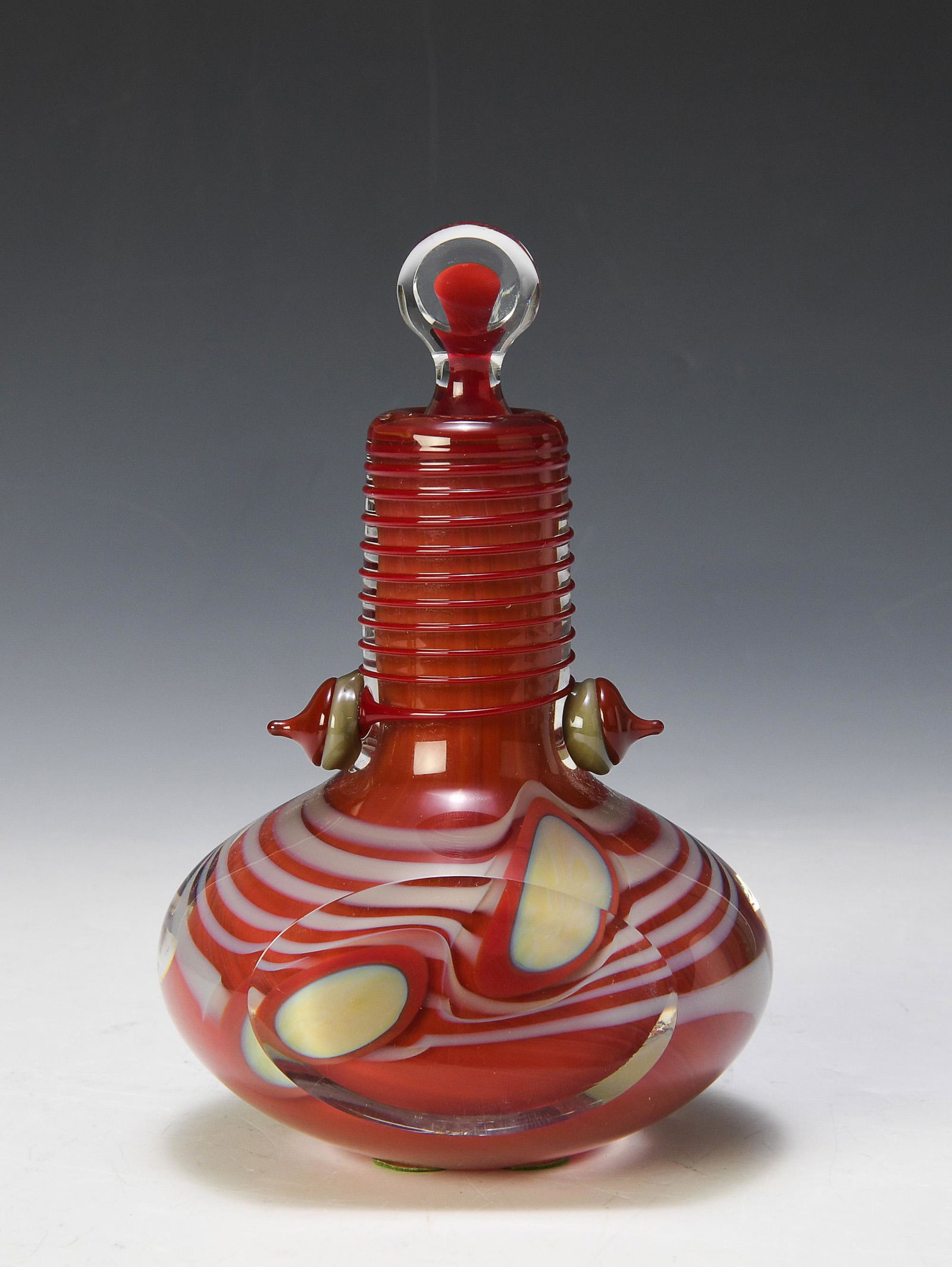 Robert Levin Studio Glass Perfume Bottle: Robert Levin studio glass perfume bottle. Red, white, and clear art glass bottle. Signed Robert Levin 1980 RLFB 036 on base. Dimensions are: 3 7/8 inches wide X 3 1/8 inches deep X 6 1/8 inches tall w