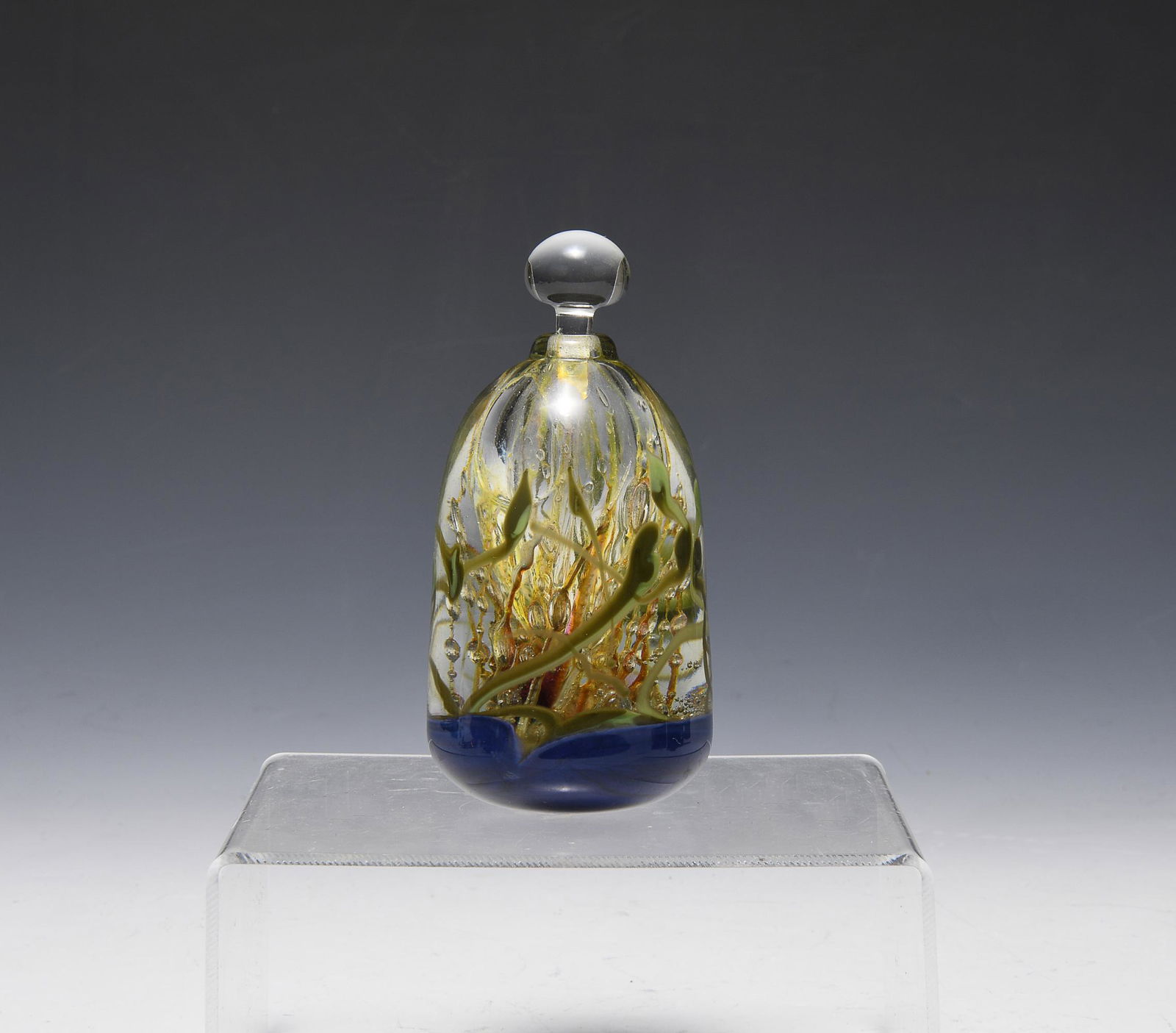 Leon Applebaum Perfume with Stopper: Leon Applebaum art glass perfume bottle in gold, green, red, blue, and clear glass, with stopper. Signed Leon Applebaum -1979 on base. Dimensions are: 2 1/4 inches diameter X 4 1/2 inches tall with st