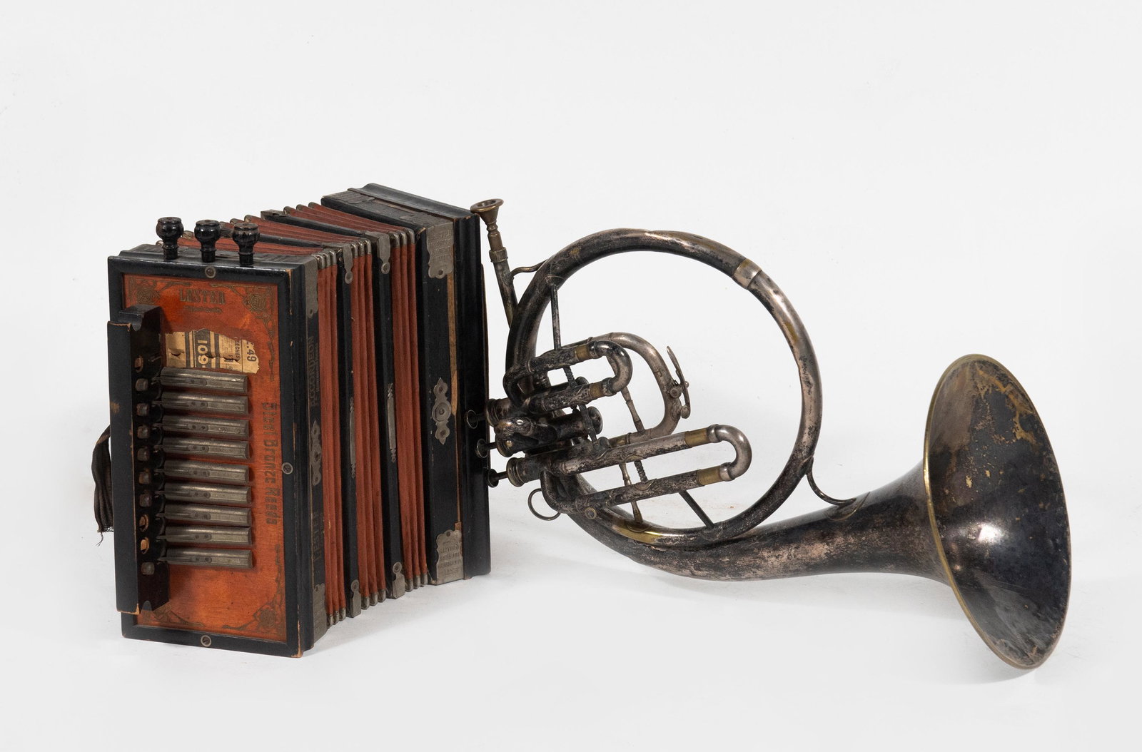 (2) Antique Lester Accordion and French Horn: Group of (2) antique musical instruments: a) Lester accordion with hammered steel bronze reeds, made in Germany, late 19th century; diatonic or Cajun style accordion, with 10 button keys on right side