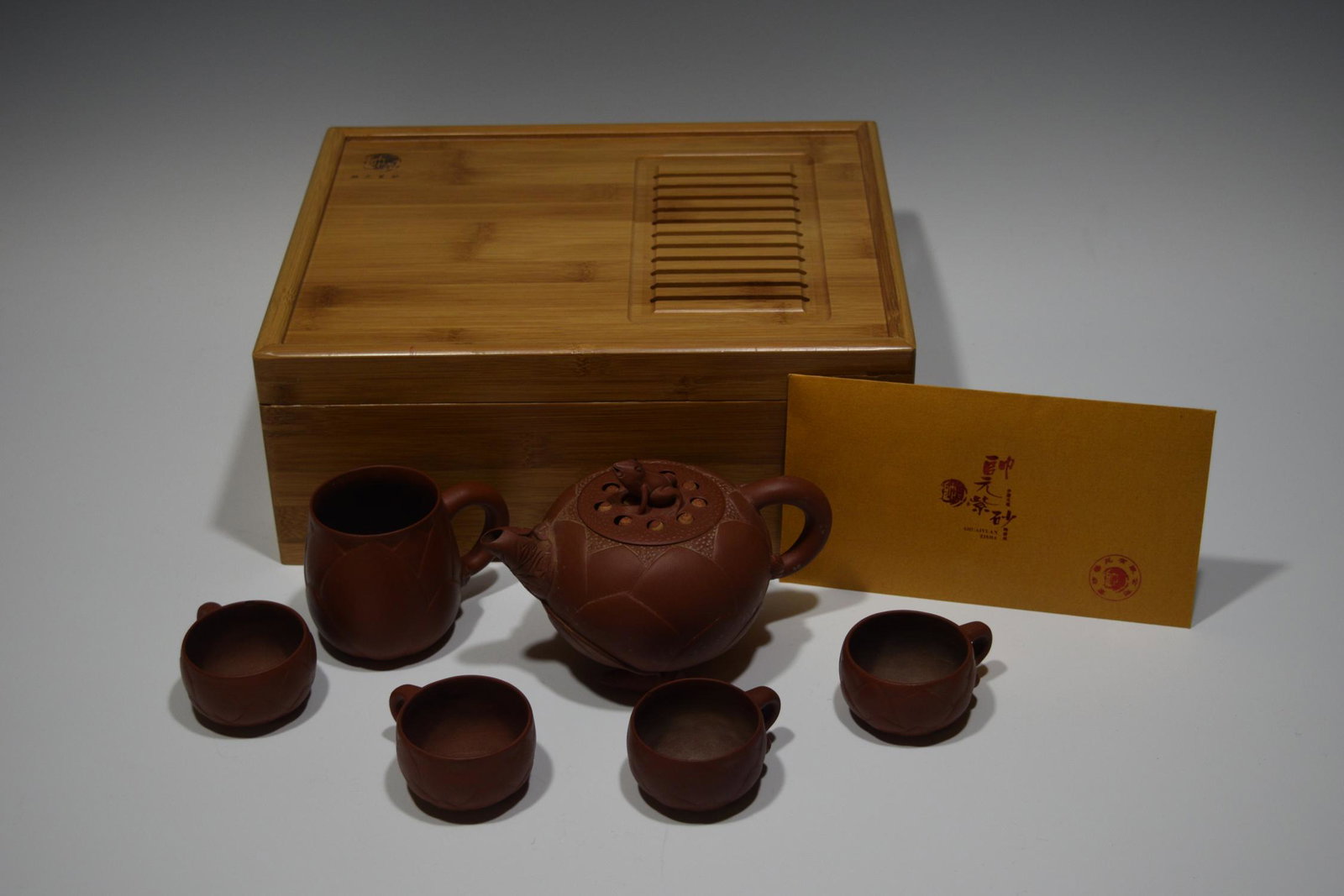 Chinese Yixing Tea Set with Lotus Flower and Frogs: Chinese Yixing tea set with lotus flower motif on teapot (4) cups and creamer, teapot lid has a frog and lotus seeds in formed bamboo box. Teapot measures: 6.75 inches long including spout and handle 